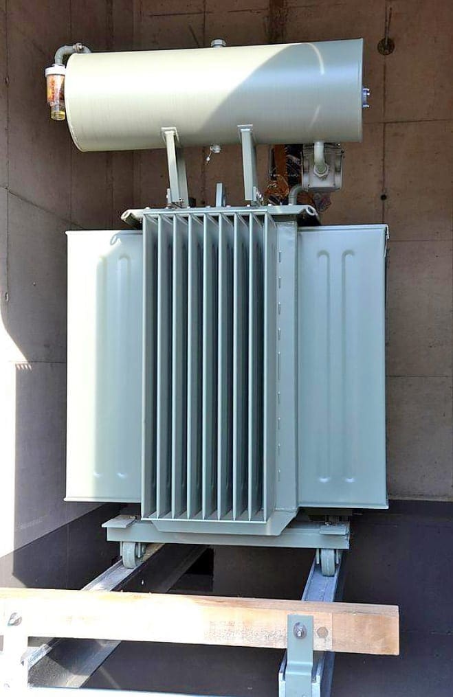 Oil transformer with air convection cooled heat exchangers in the front and at the side