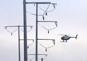 A helicopter starts the process of stringing a high-voltage transmission line